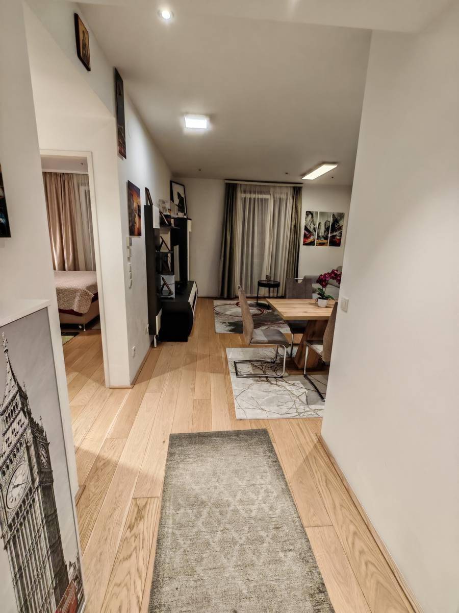Heller Flur mit Holzboden, der zum offenen Wohnbereich und Schlafzimmer führt.