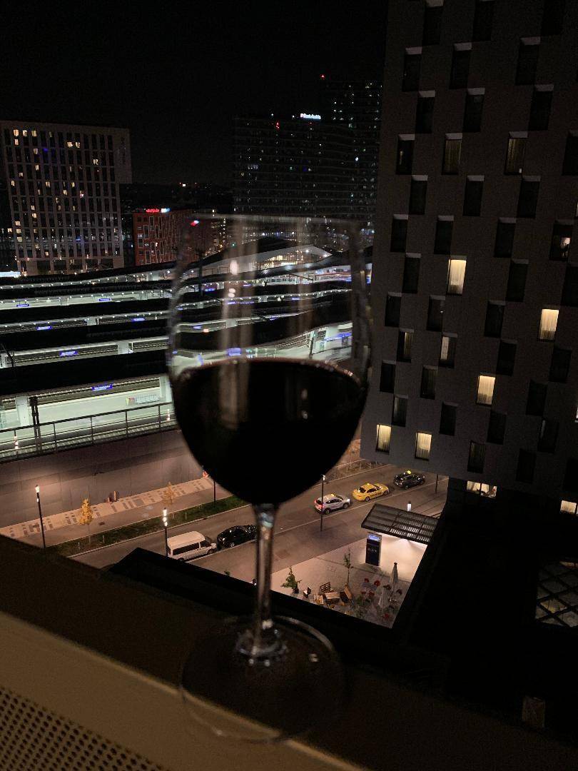 Abendlicher Ausblick vom Balkon auf die beleuchtete Stadt und umliegende Gebäude.