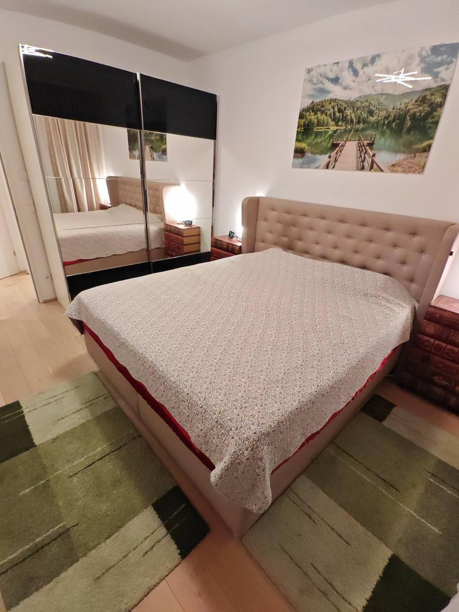 Schlafzimmer mit großem Bett und einem modernen Spiegelschrank für viel Stauraum.