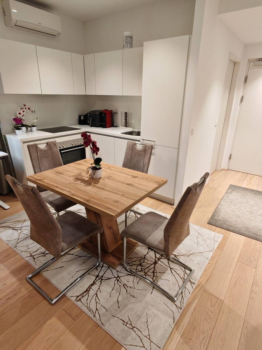 Moderne Einbauküche mit weißen Fronten, integrierten Geräten und Essbereich.