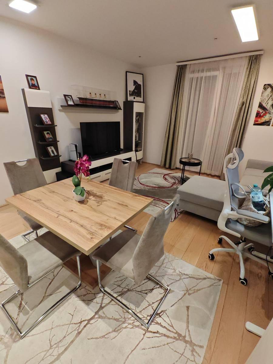 Heller Wohnbereich mit bequemer Couch, Esstisch und modernem Entertainment-System.