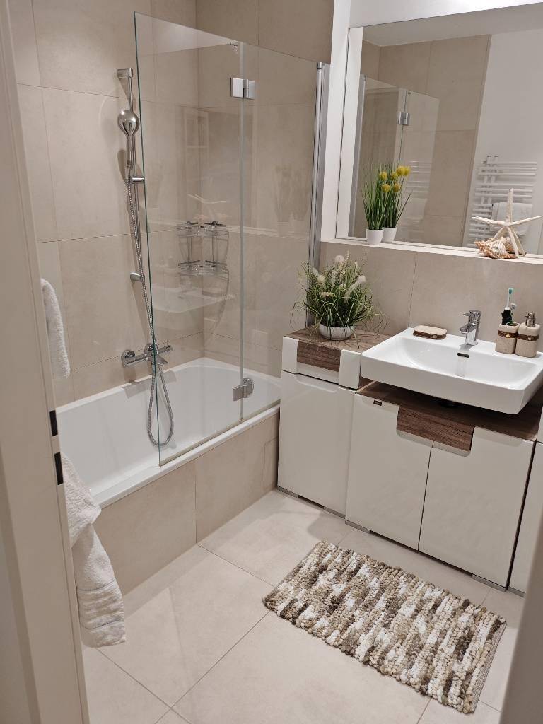 Modernes Badezimmer mit Badewanne, Duschwand und elegantem Waschtisch.