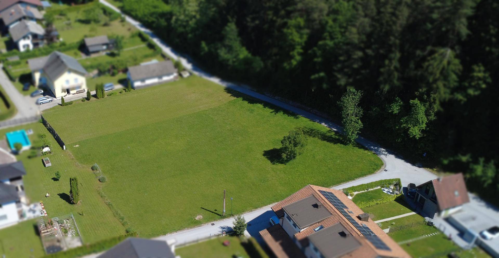 Panoramische Luftaufnahme eines unbebauten Grundstücks, umgeben von Wohnbebauung und Natur.