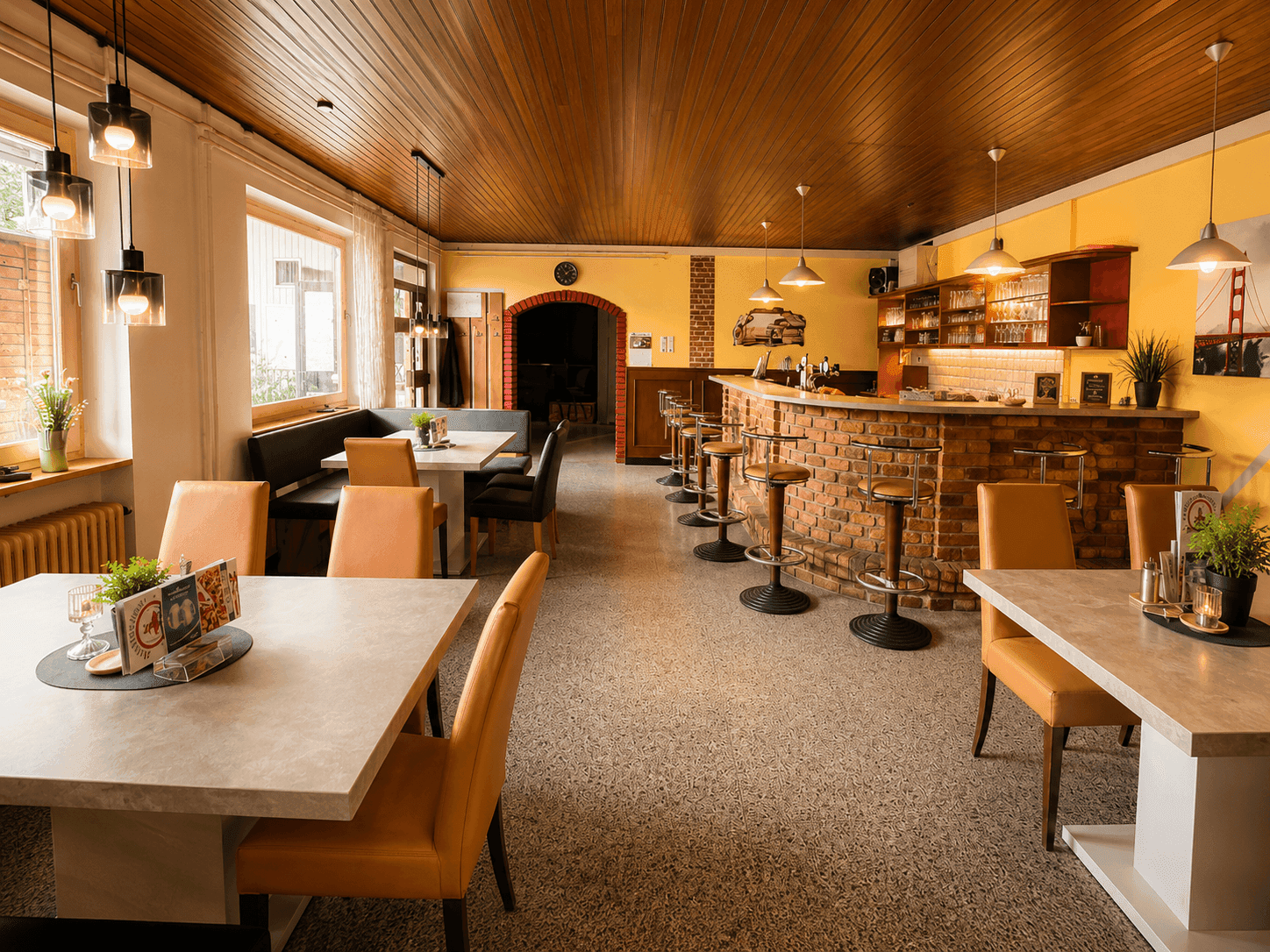 Geräumiger Restaurantbereich mit Tischen, Stühlen, einer Bar und Holzdeckenverkleidung.