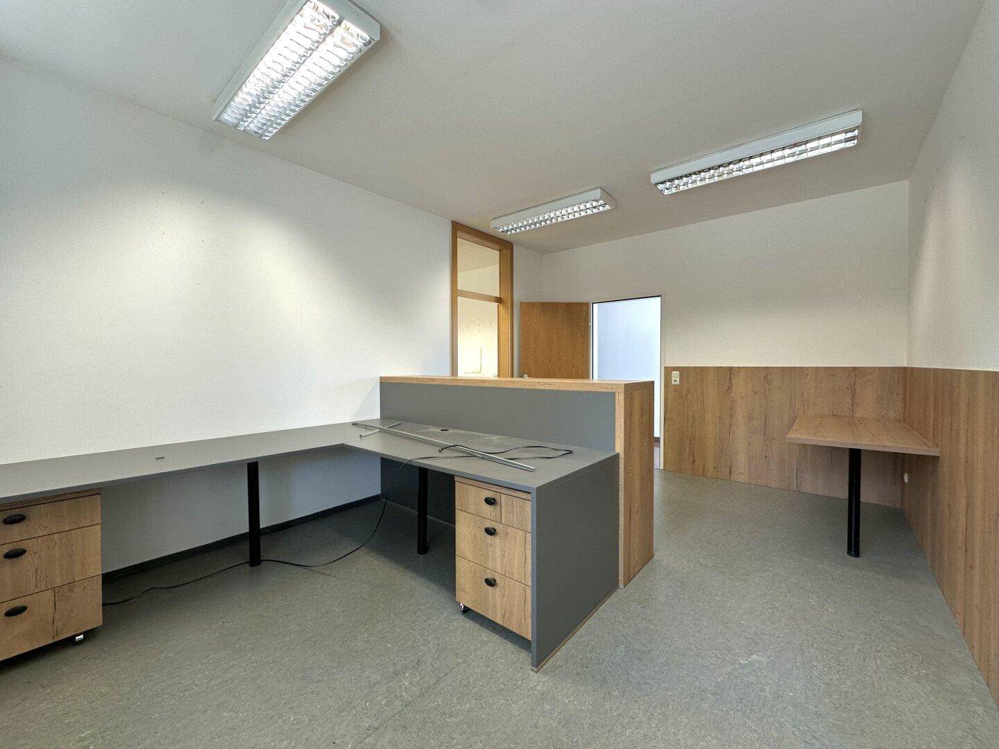 Modernes Büro mit Schreibtischen, Holzvertäfelung und einem Fenster.