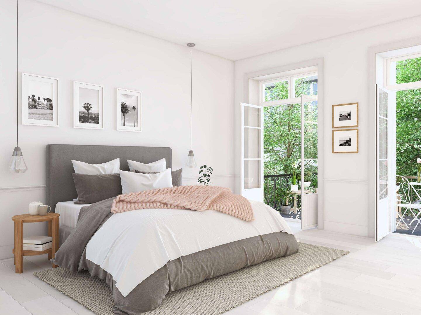 Helles Schlafzimmer mit Zugang zu einem kleinen Balkon und Blick ins Grüne.