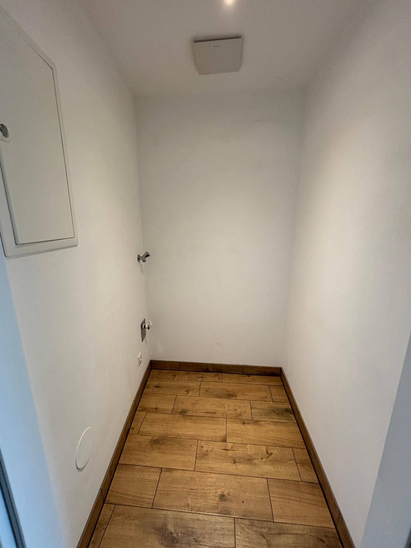 Praktischer Hauswirtschaftsraum mit Anschlüssen für Waschmaschine und Trockner, ausgestattet mit Holzboden.