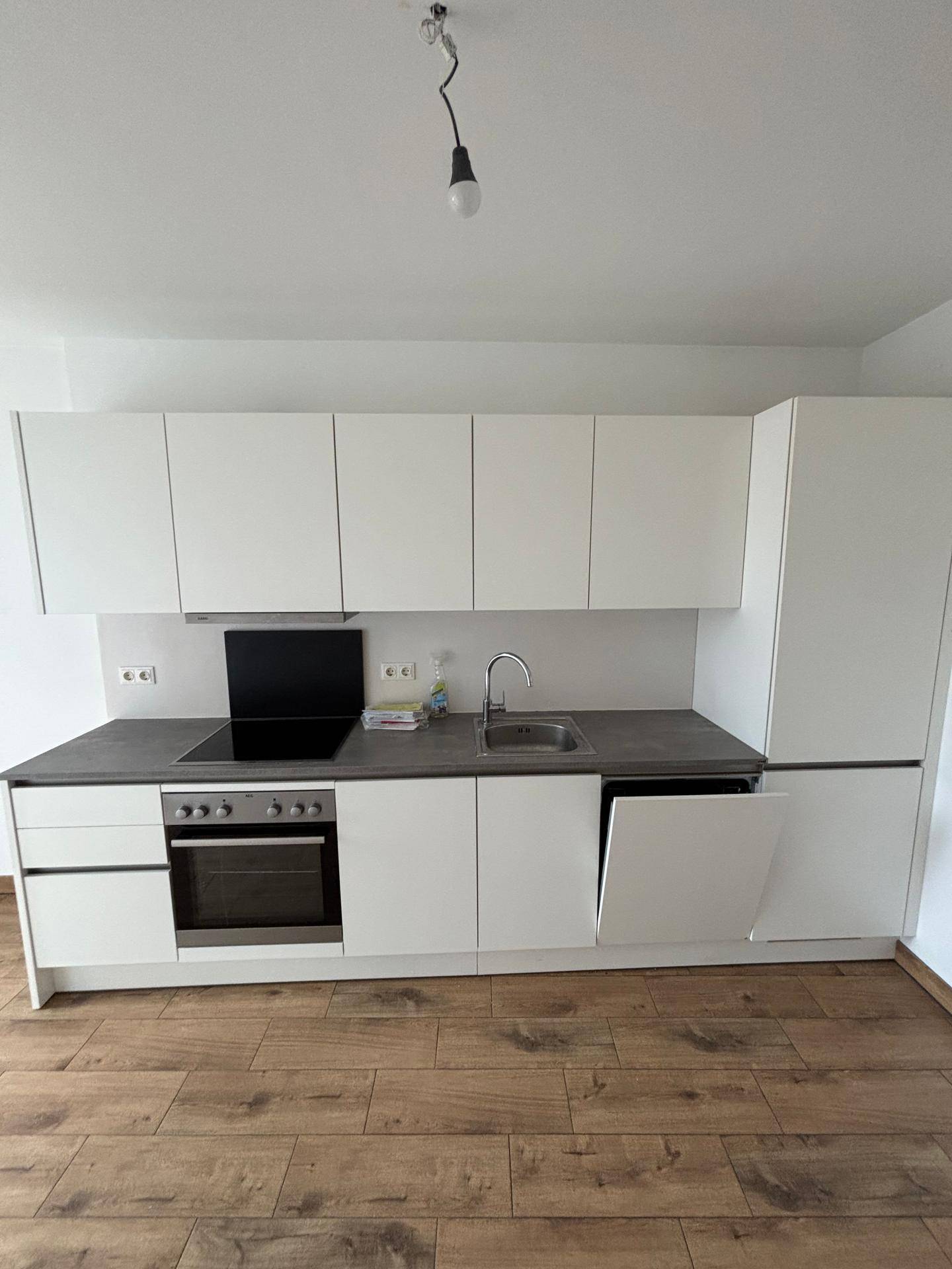 Detailansicht der modernen Einbauküche mit weißen Fronten, Spüle, Induktionskochfeld und Backofen.