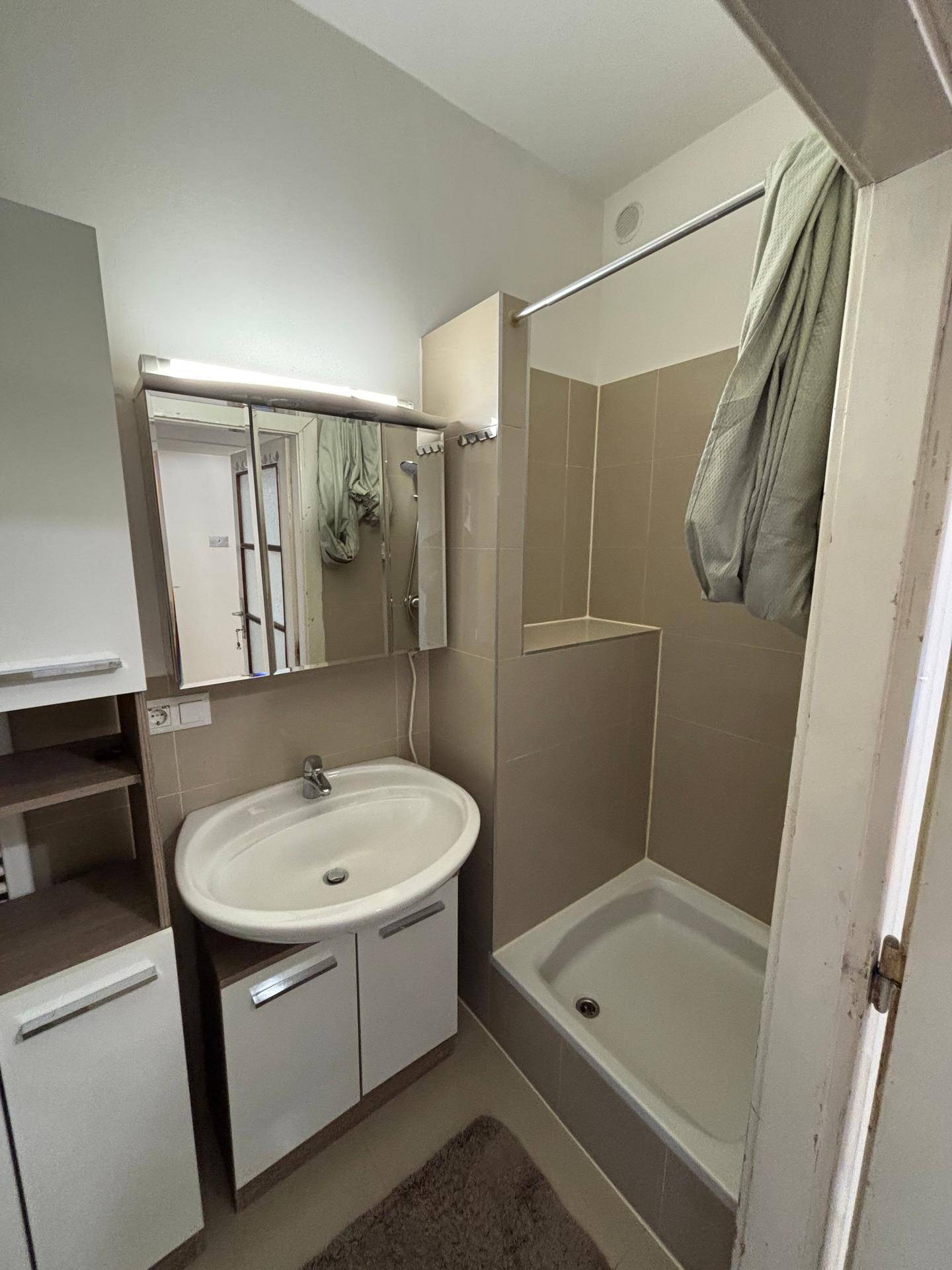 Kleines Badezimmer mit Duschkabine, Waschbecken und Spiegelschrank, funktional eingerichtet.