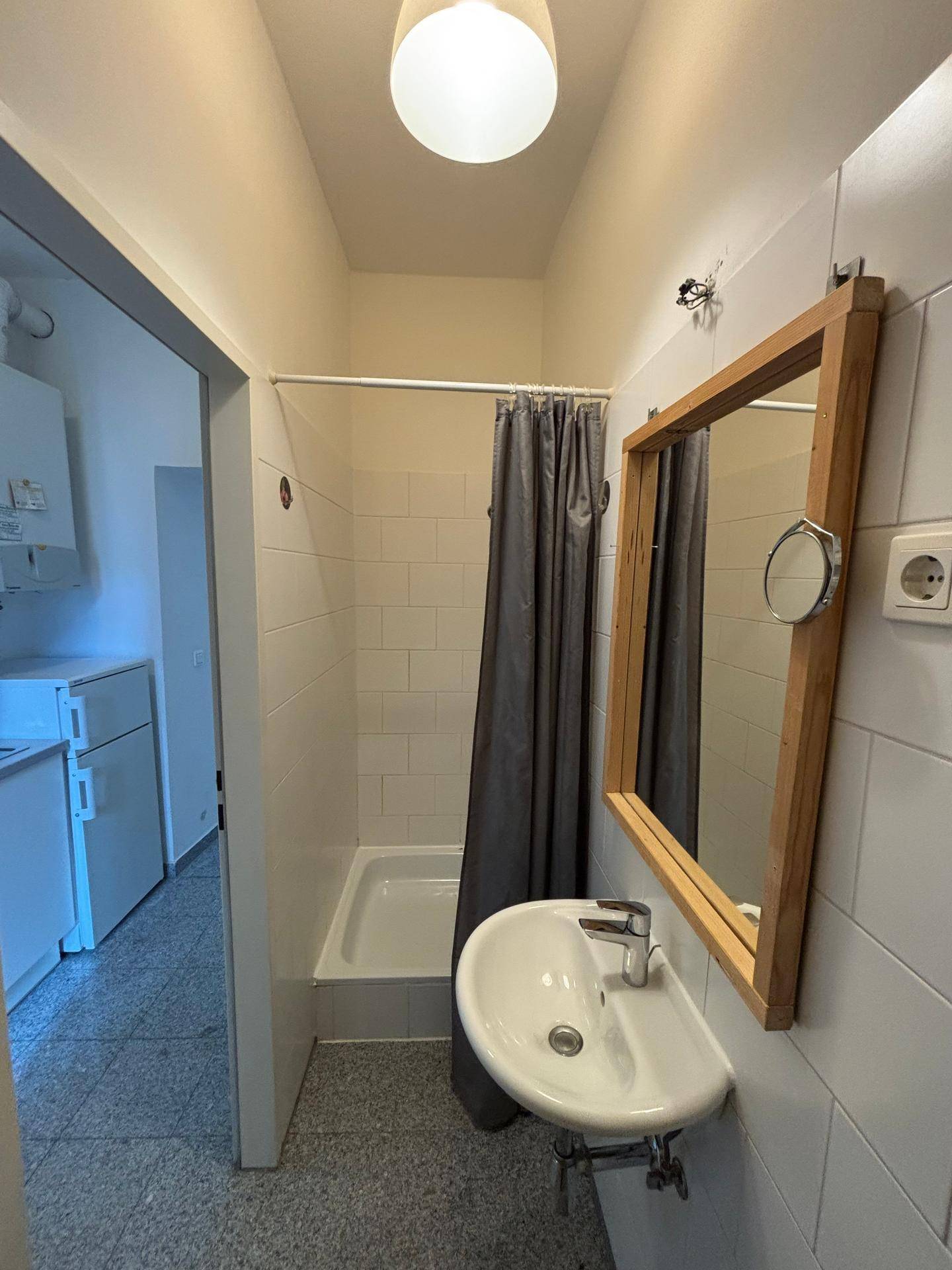 Badezimmer mit Waschbecken, Duschbereich und beheiztem Handtuchhalter, praktisch eingerichtet.