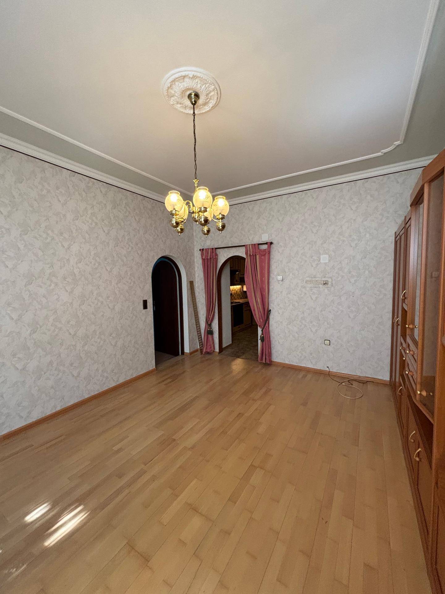Wohnzimmer mit Parkettboden, Stuckdecke und eleganten Durchgängen zu anderen Räumen.