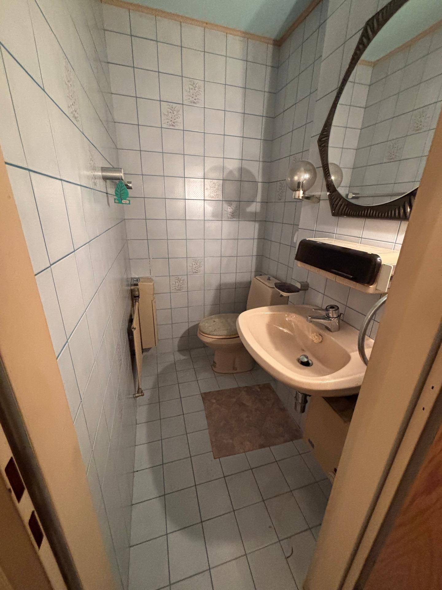 Kleines WC mit hellblauen Fliesen, Toilette und Waschbecken in Pastellfarben aus den 80ern.