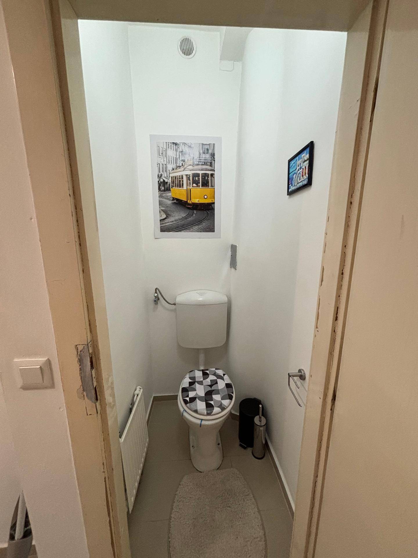 Separates WC mit Toilette und Heizkörper, dekoriert mit einem Bild an der Wand.