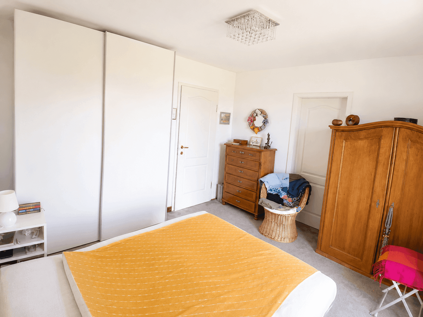 Schlafzimmer mit Teppichboden, großen weißen Kleiderschränken und einem Kronleuchter.