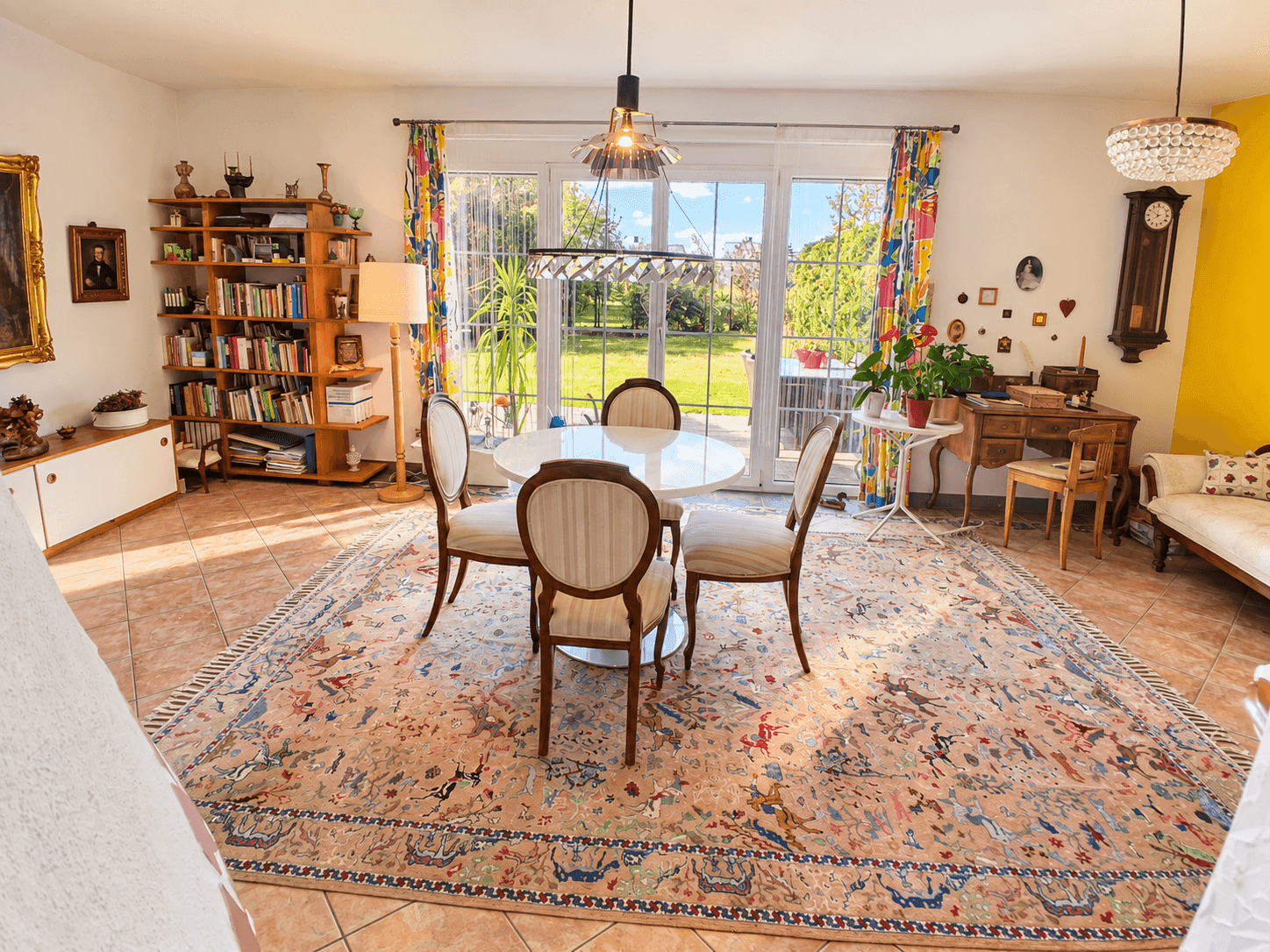 Lichtdurchfluteter Wohn- und Essbereich mit Bücherregal und direktem Zugang zum Garten.