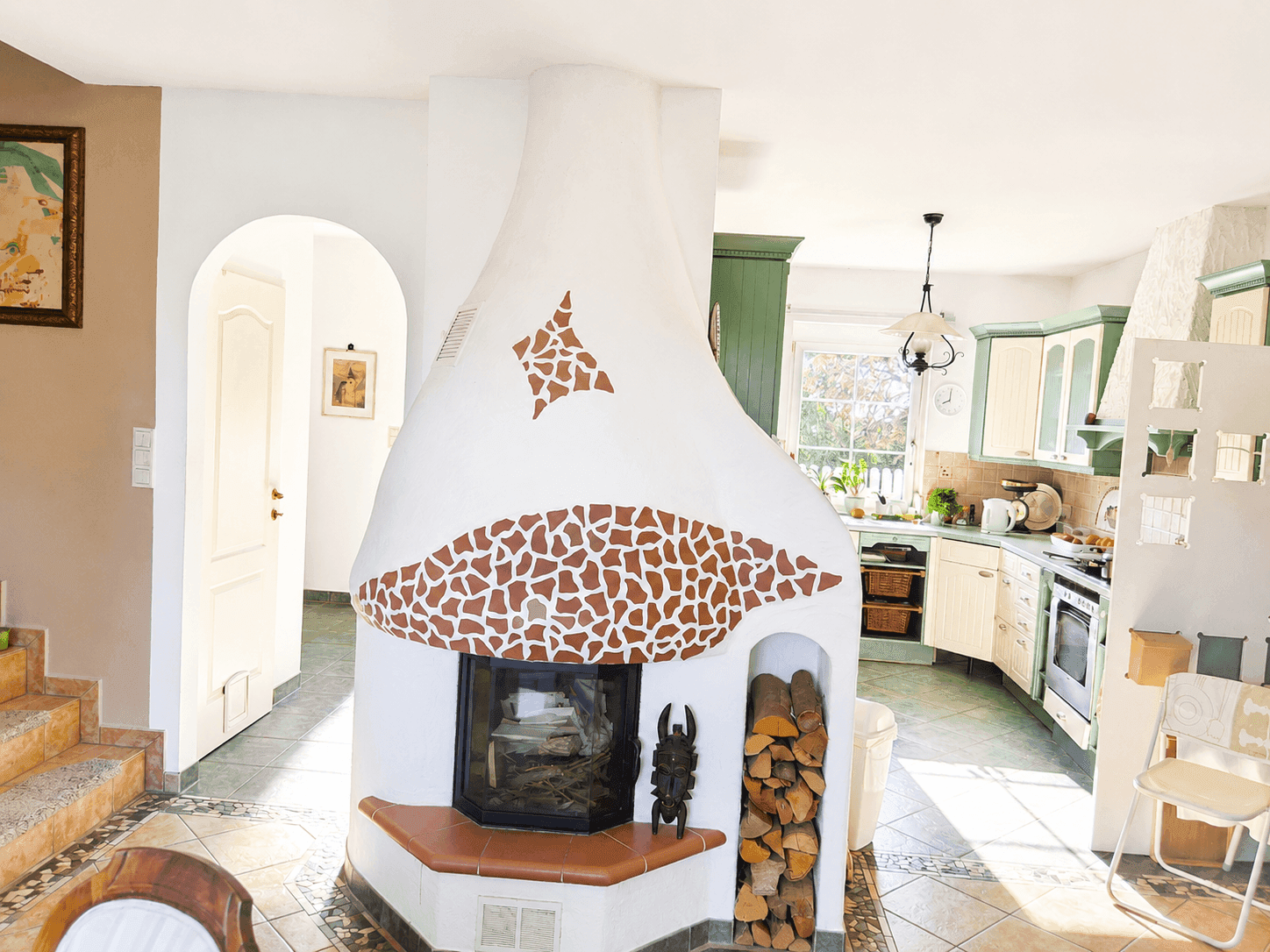 Helle Küche mit integriertem Kamin und traditionellen Schränken in Grün- und Cremetönen.