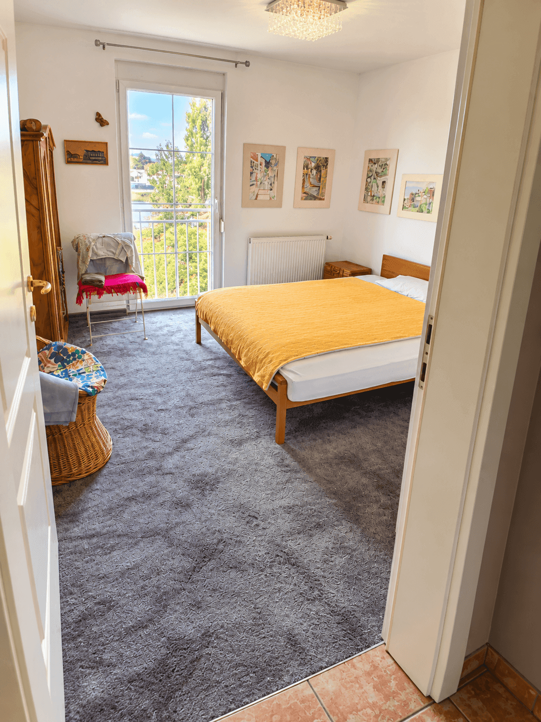 Helles Schlafzimmer mit Teppichboden und französischem Balkon mit Blick ins Grüne.
