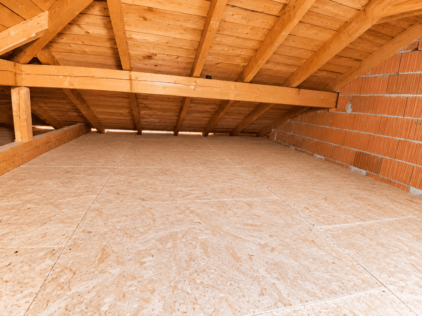 Geräumiger Dachboden mit OSB-Bodenplatten und sichtbarer Holzkonstruktion des Daches.