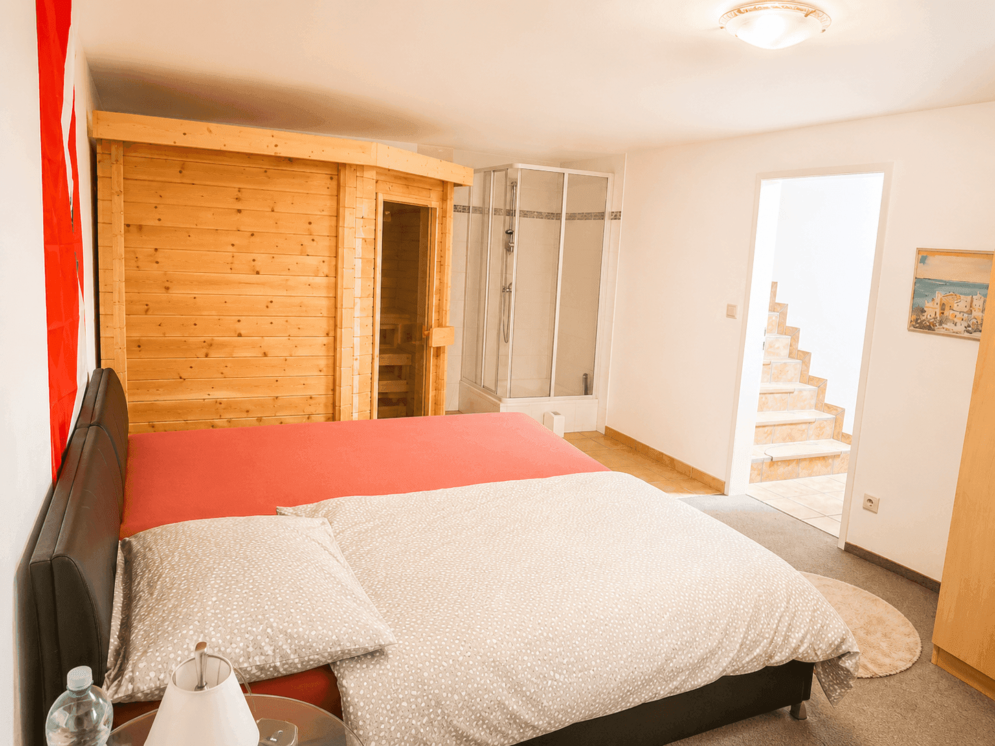 Schlafzimmer mit Doppelbett, integrierter Sauna und Duschkabine, ideal für Wellness.
