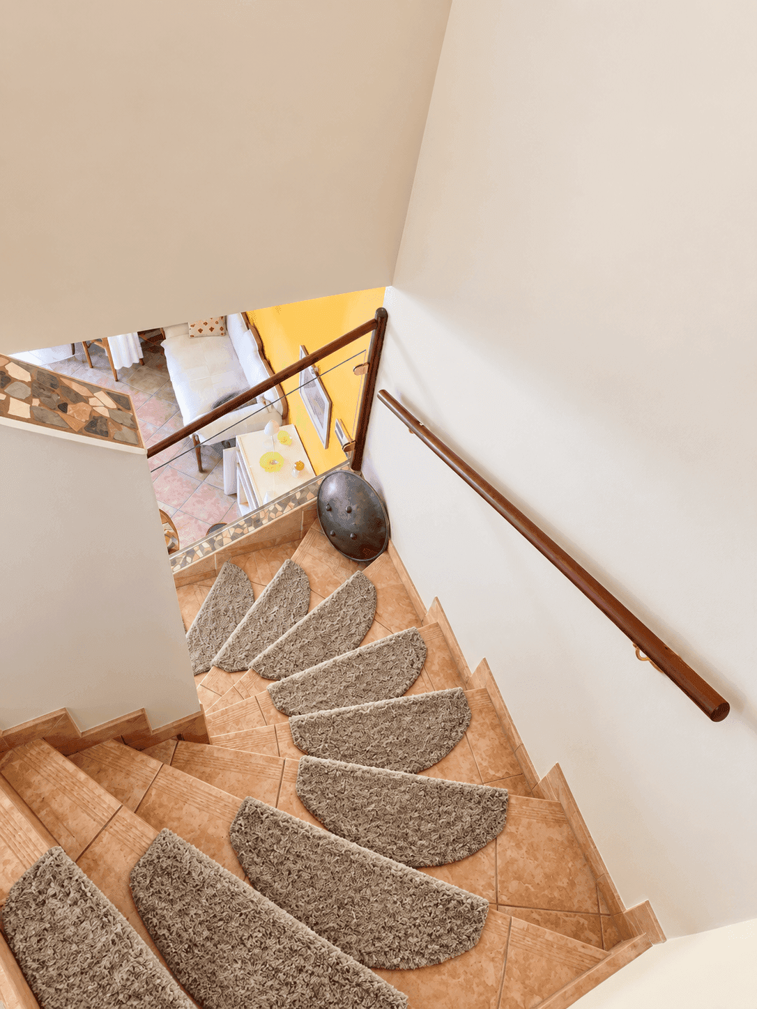 Wendeltreppe mit Teppichstufen und hellem Geländer.