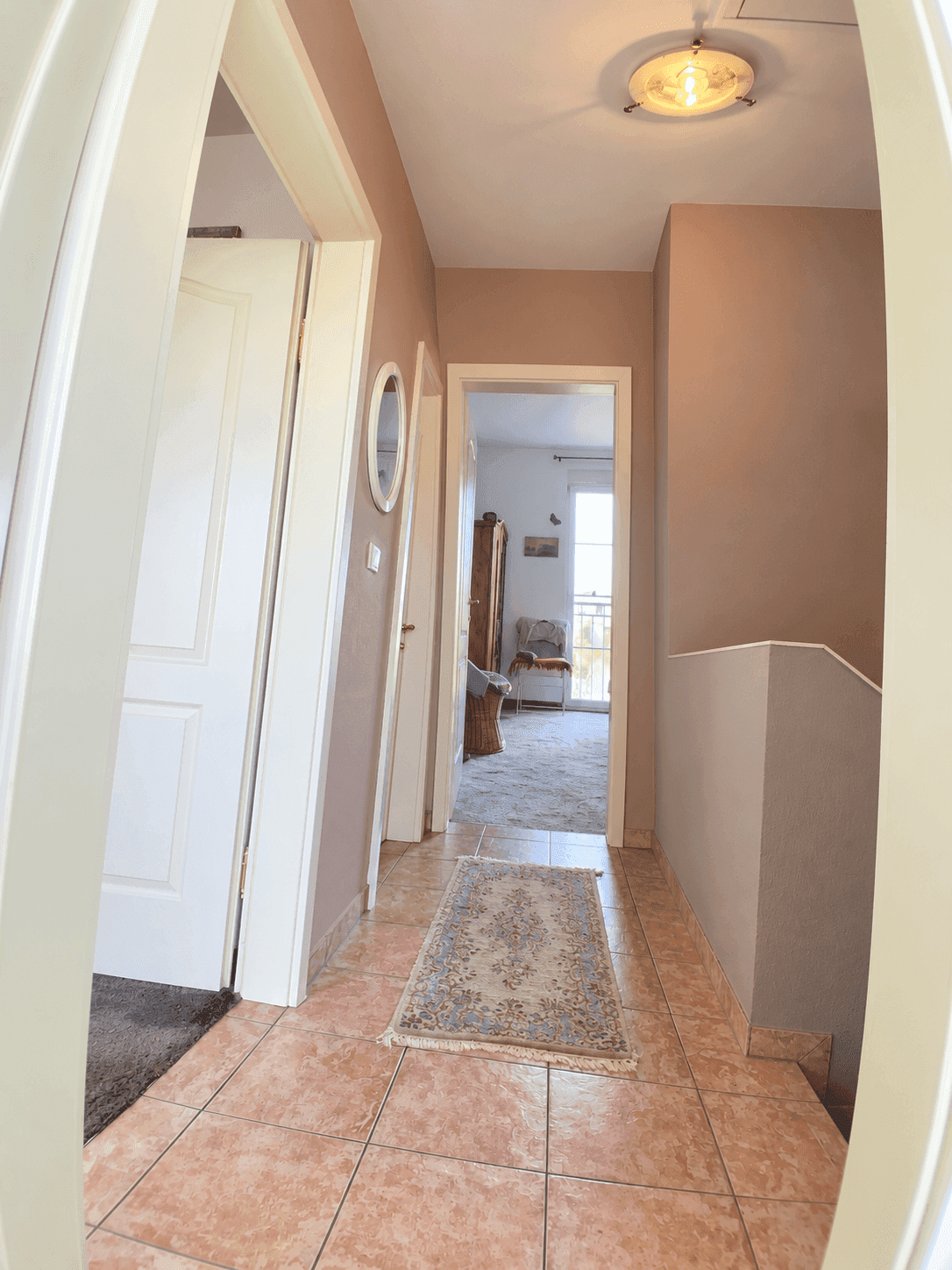 Obergeschossflur mit Fliesenboden und Blick in ein angrenzendes Zimmer.