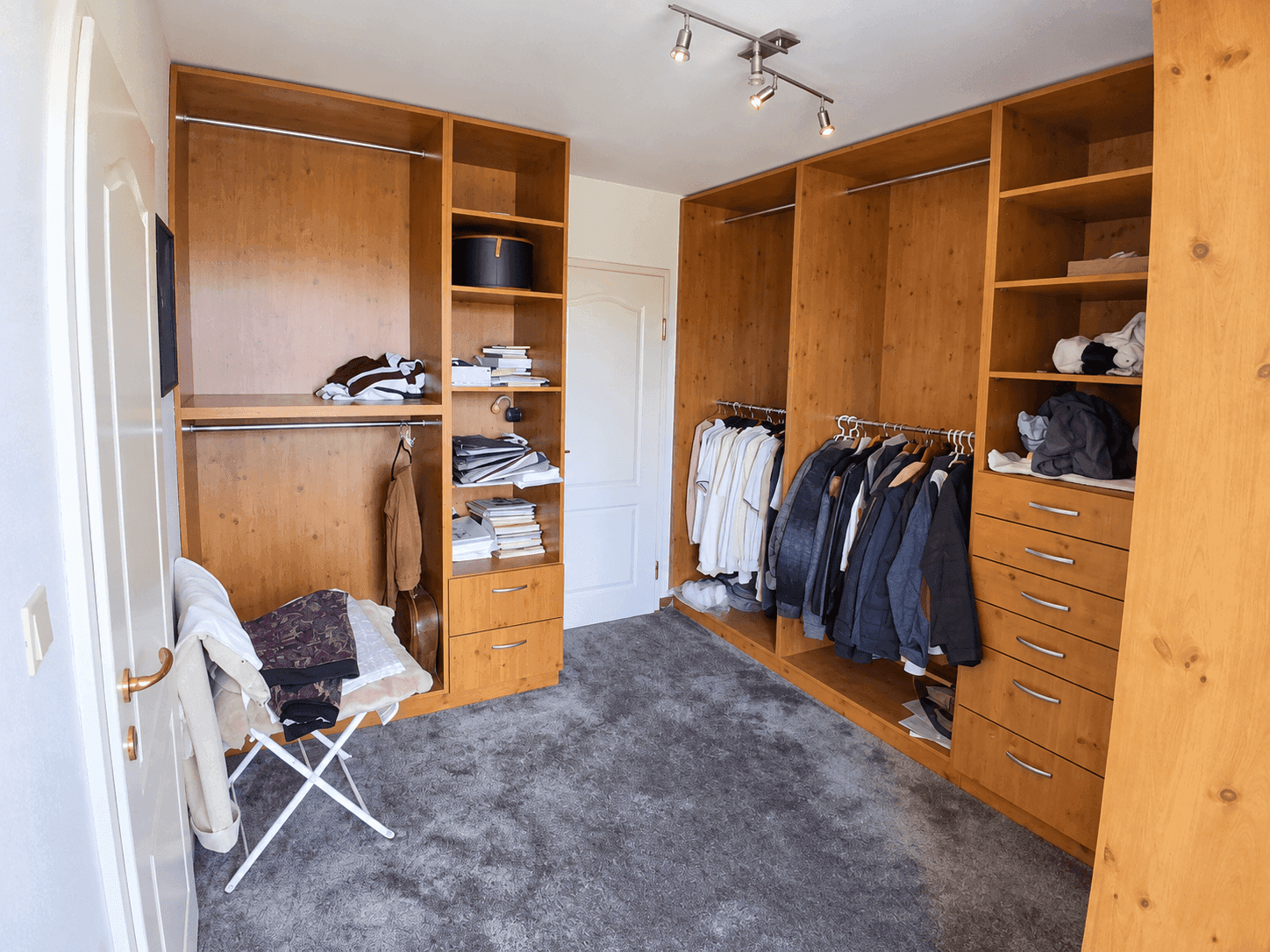 Begehbarer Kleiderschrank mit Holzregalen und Kleiderstangen für organisierte Aufbewahrung.