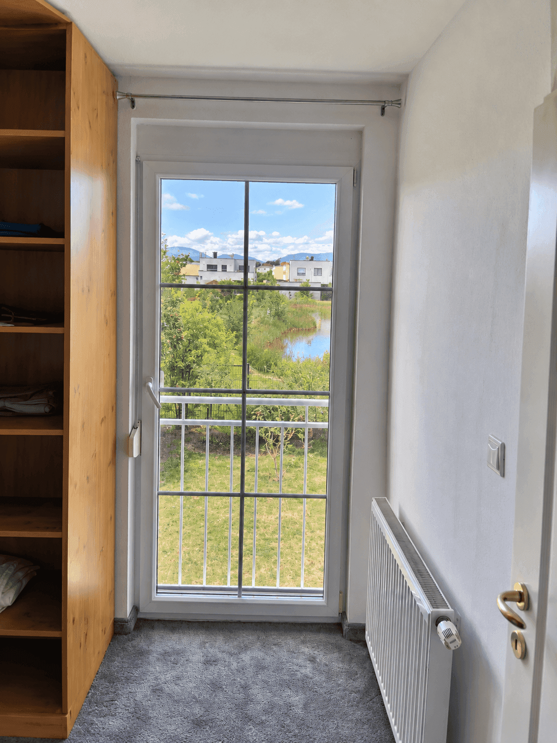Begehbarer Kleiderschrank mit Fenster und Heizung, bietet Blick ins Grüne.