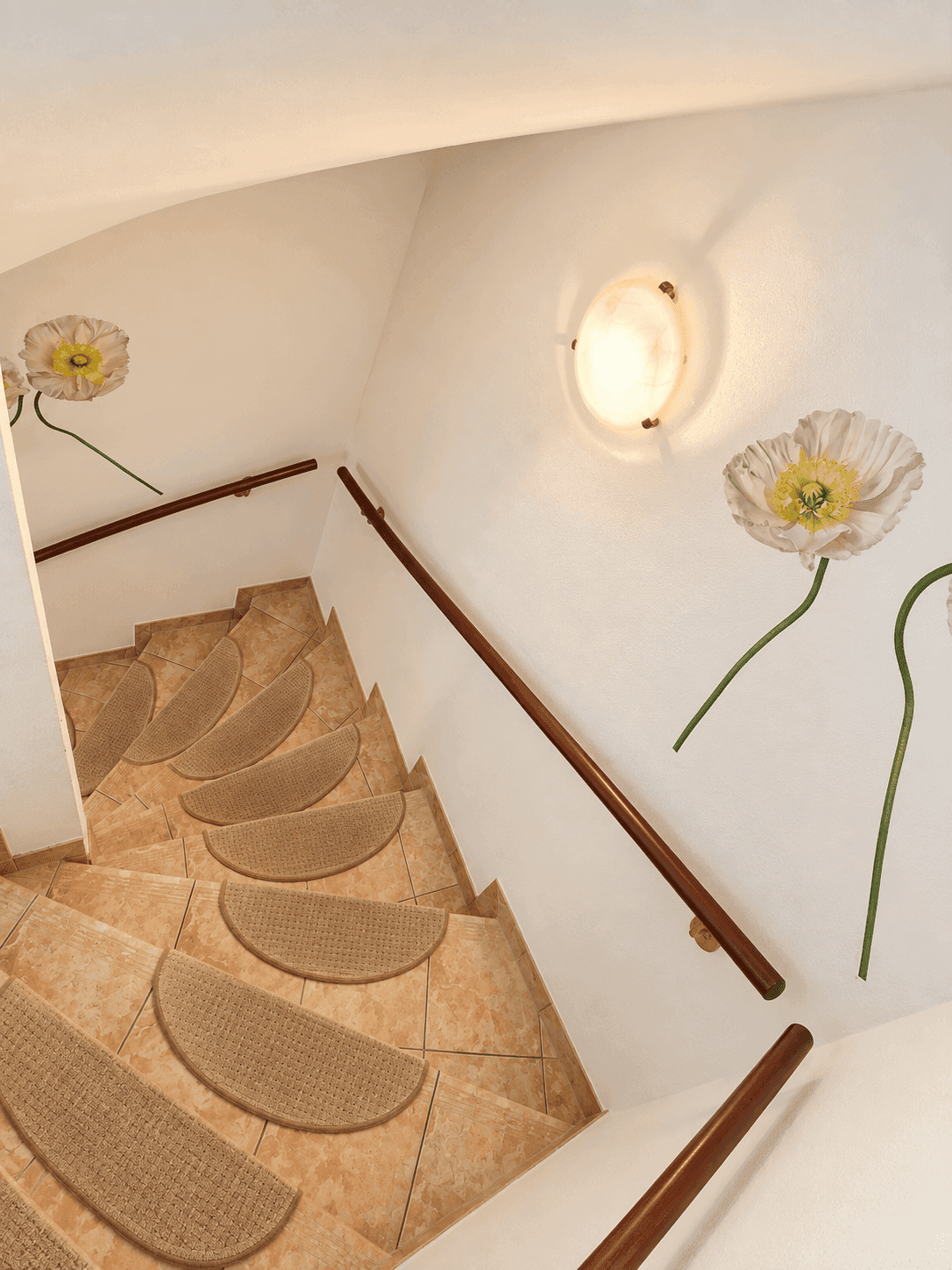 Helles Treppenhaus mit Fliesenboden, Teppichstufen und dekorativen Blumen an der Wand.