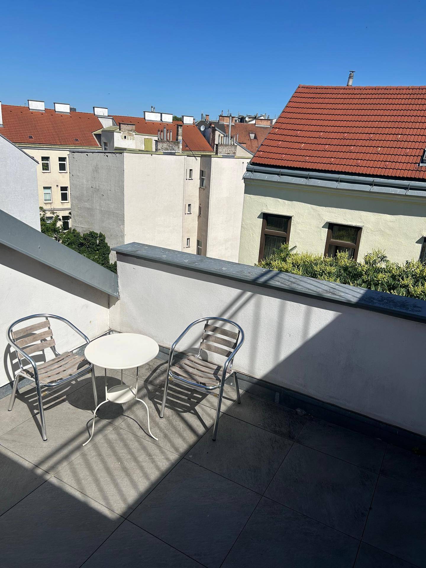 Kleine Terrasse mit Sitzgelegenheiten und Blick über die Dächer der Stadt.