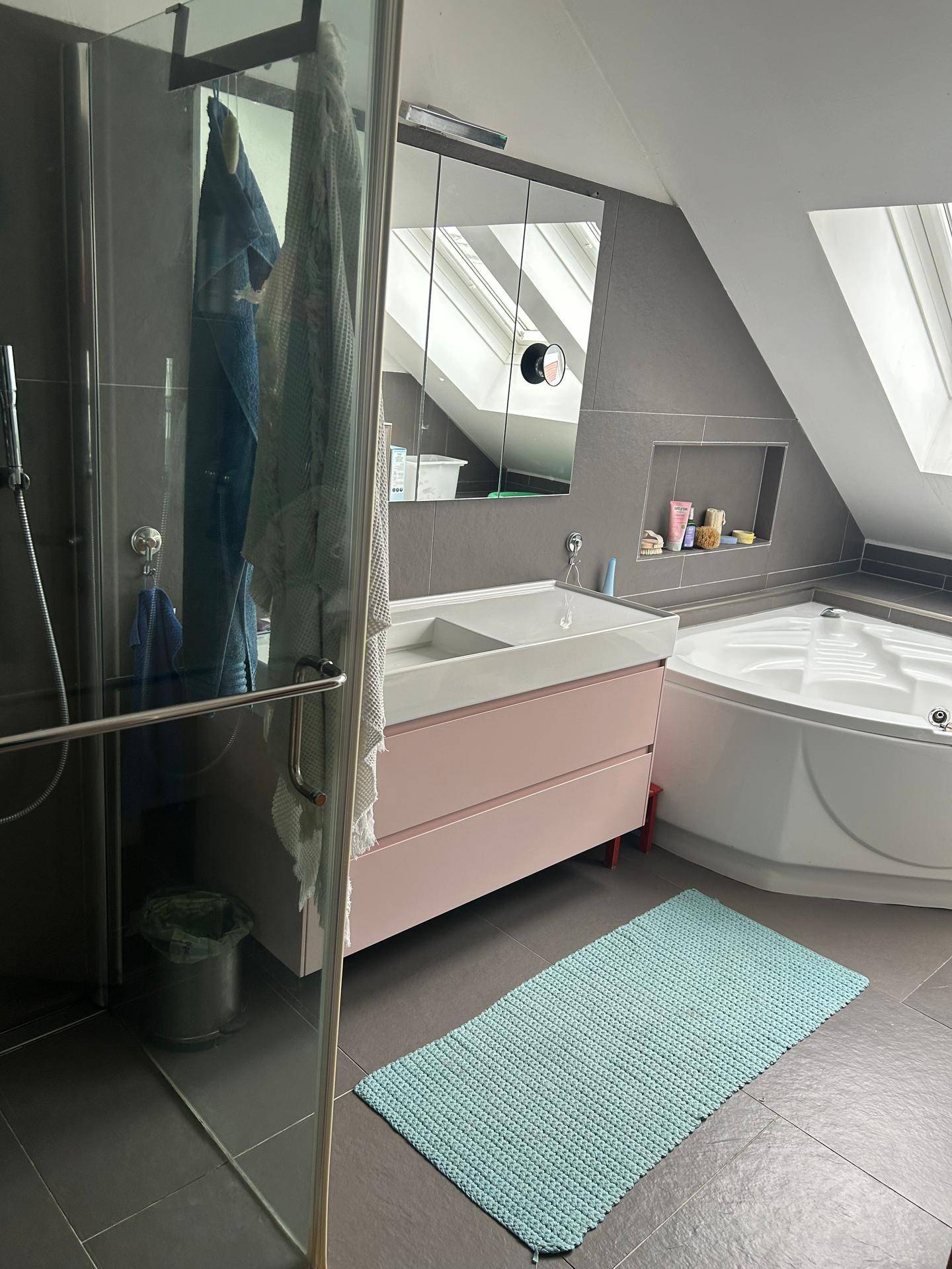 Helles Badezimmer mit Dachfenster, moderner Einrichtung, Duschkabine und Eckbadewanne.