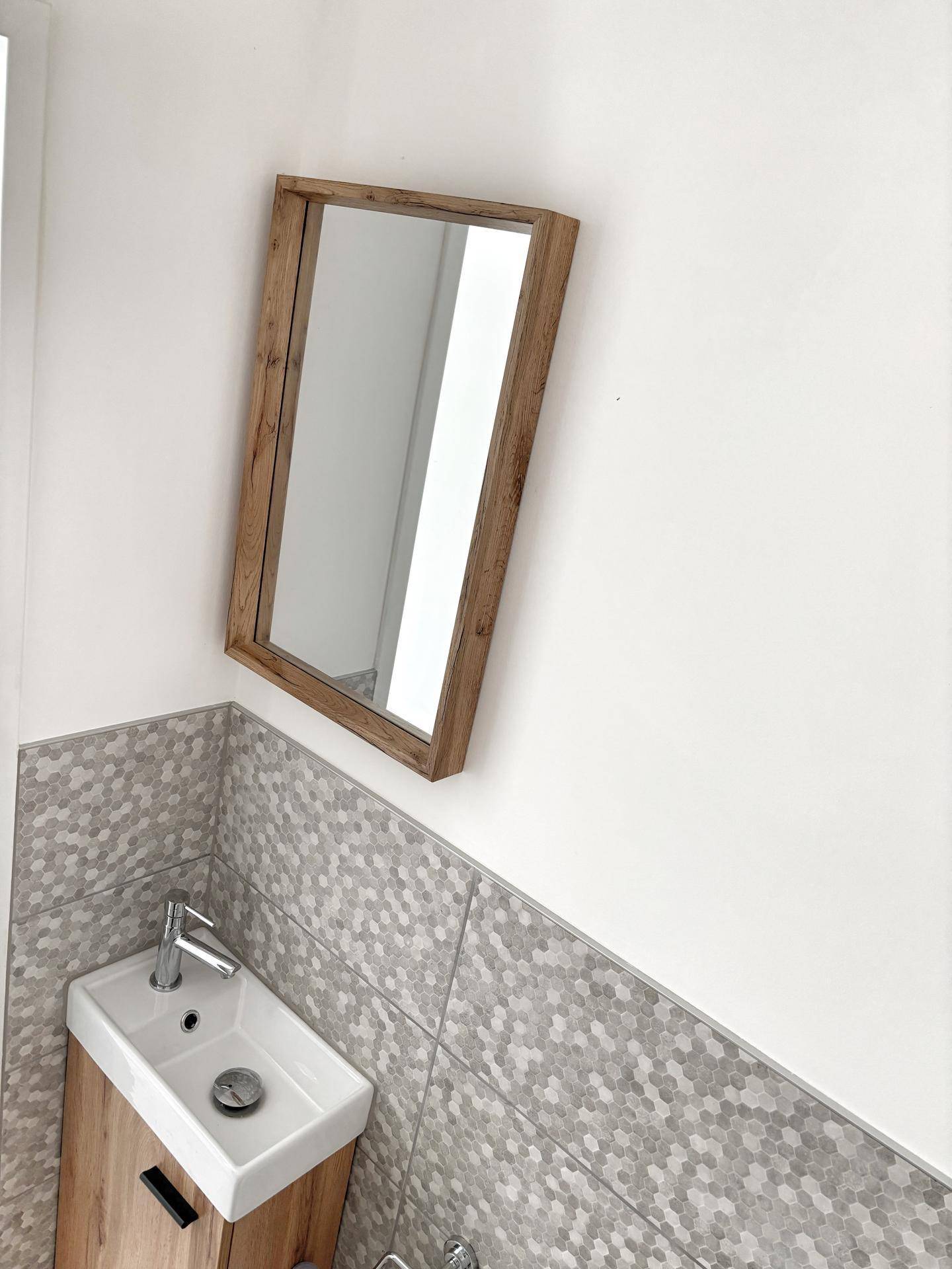 Modernes Gäste-WC mit kleinem Waschbecken, Holzunterschrank und sechseckigen Fliesen.