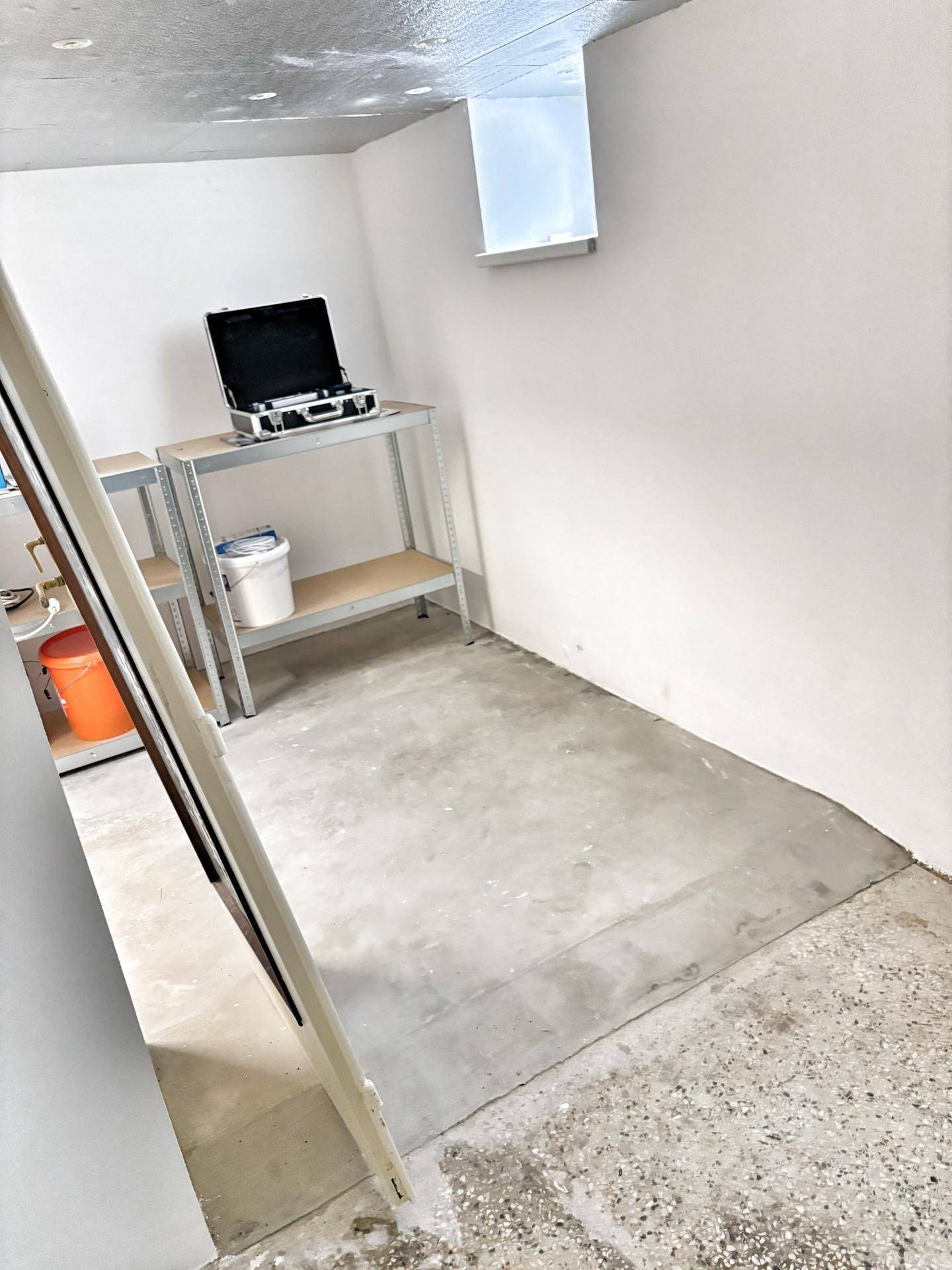 Funktionaler Abstellraum mit Betonboden und Regalen, bietet zusätzlichen Stauraum für Haushaltsgegenstände.