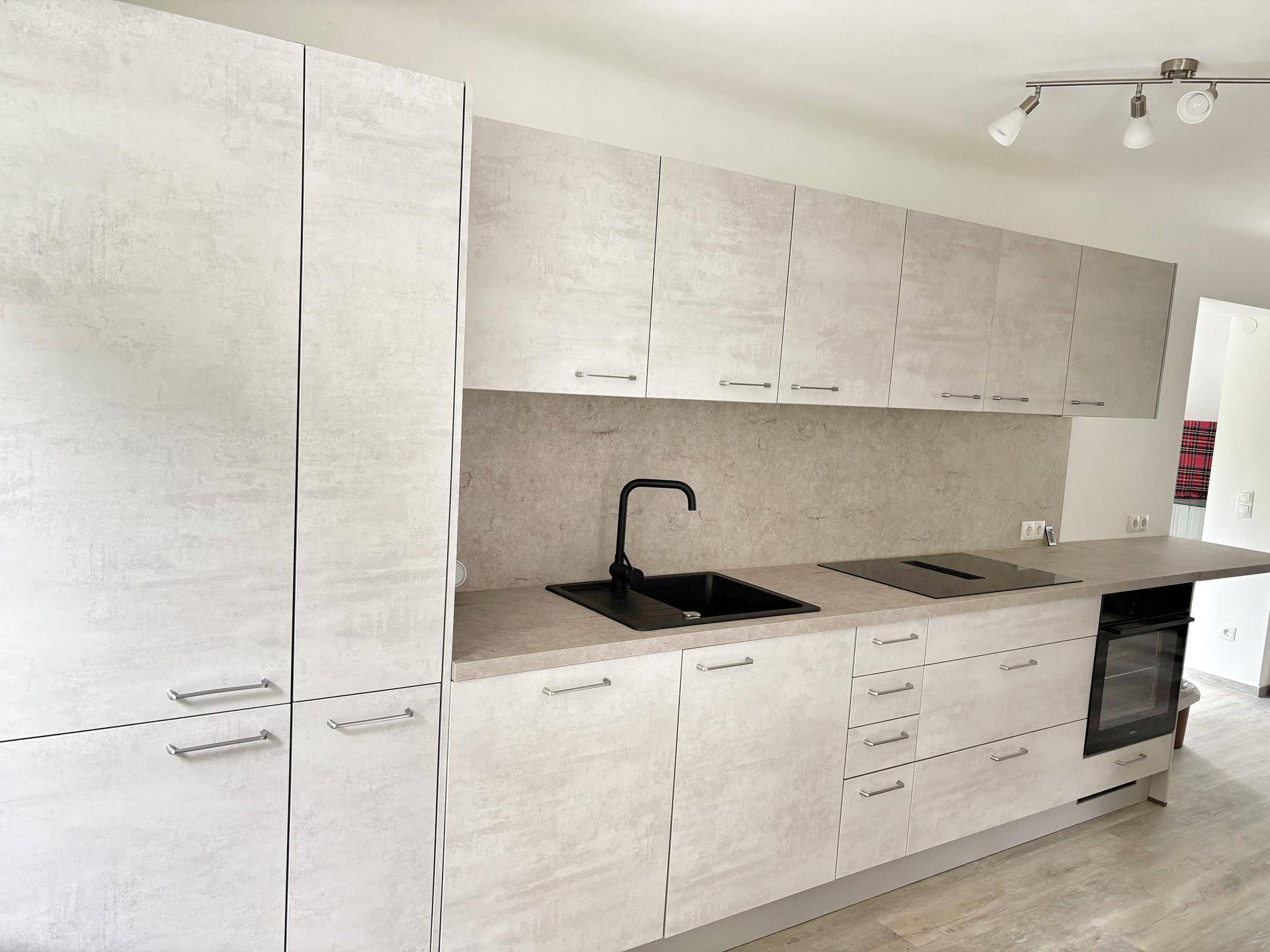 Moderne Einbauküche mit hellgrauen Fronten, schwarzer Spüle und integrierten Geräten.