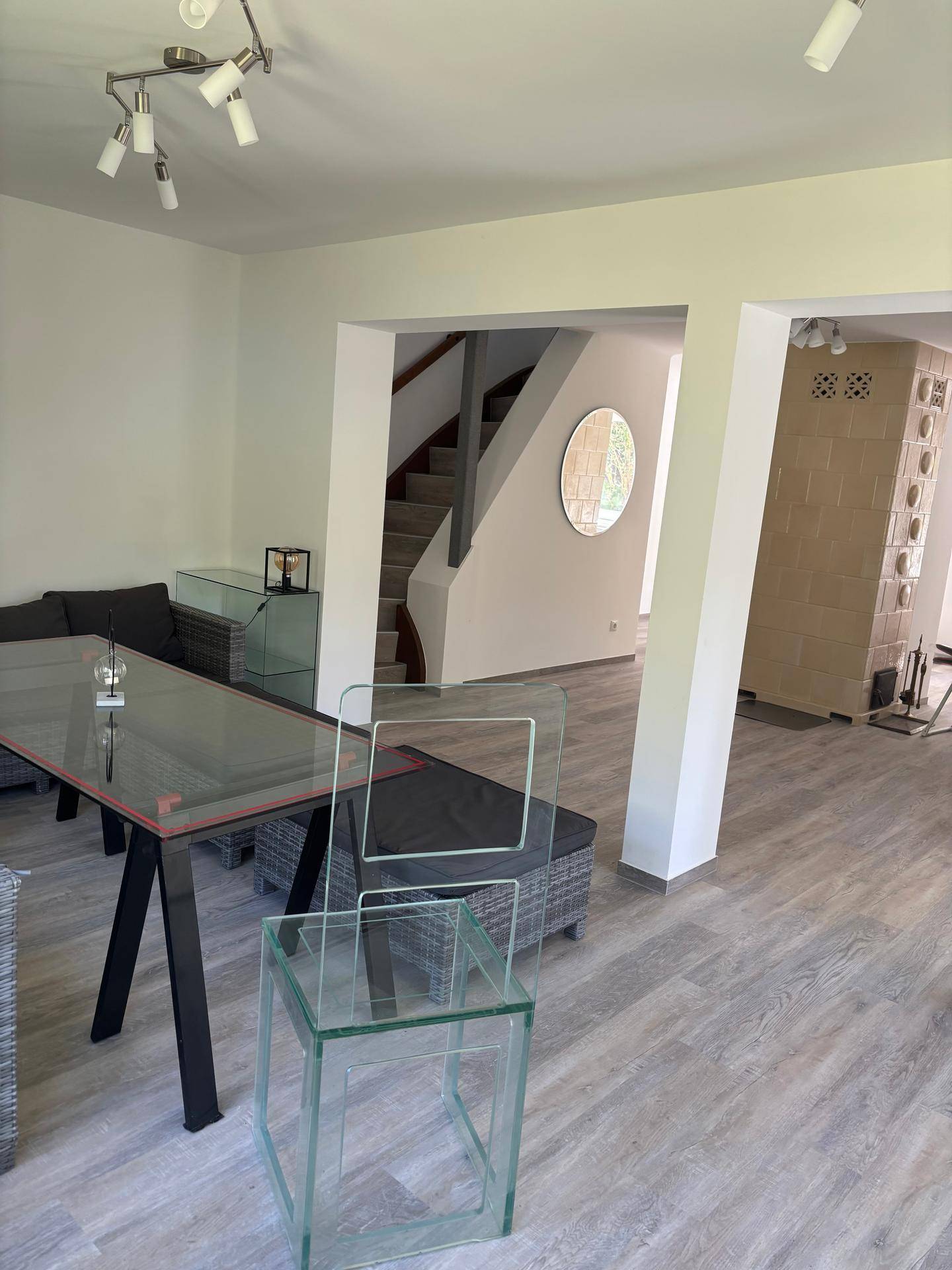 Offener Wohnbereich mit Blick auf die Treppe und den Kachelofen, ausgestattet mit modernem Laminatboden.
