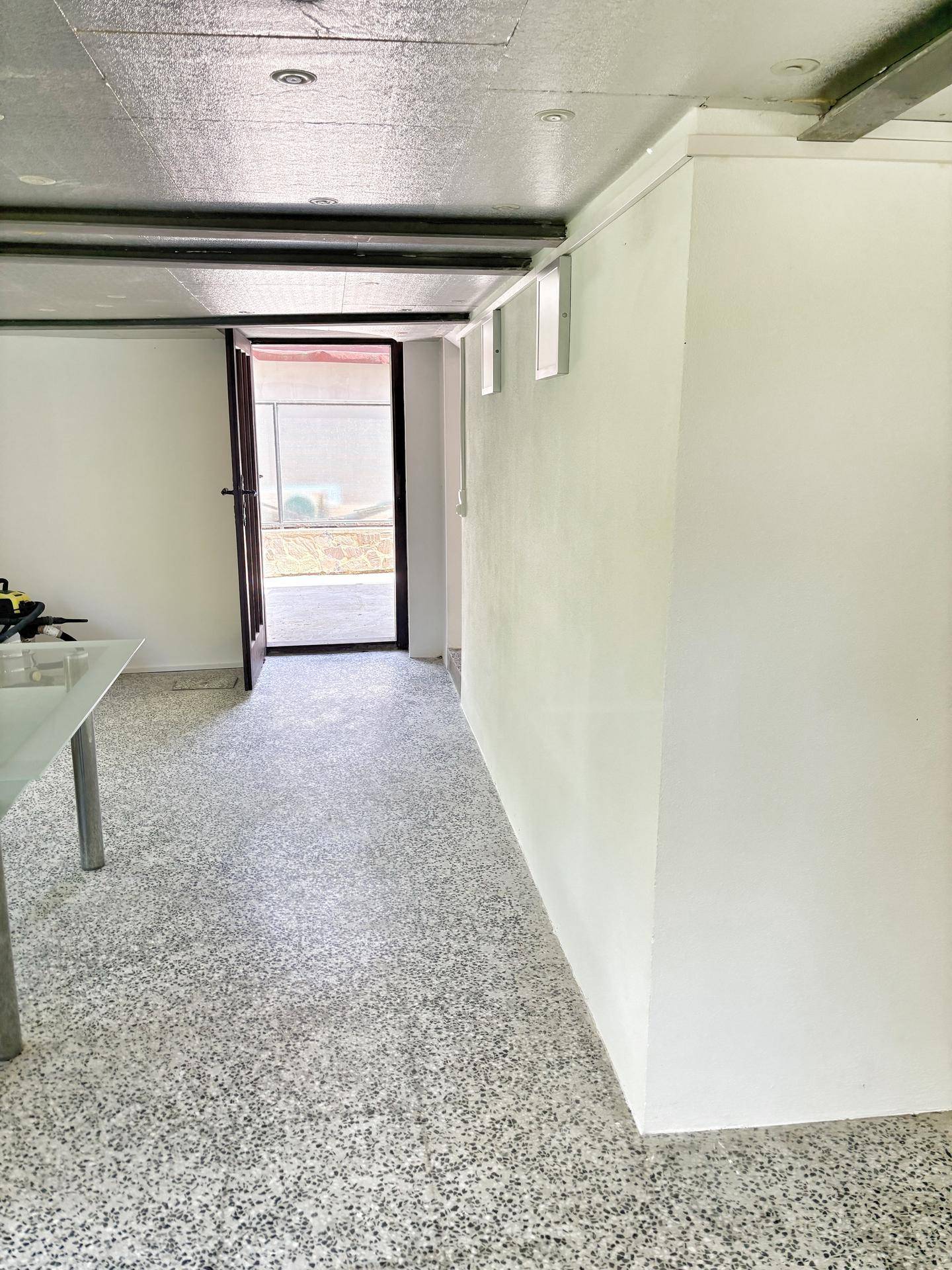 Heller Raum mit Terrazzoboden und direktem Zugang nach draußen, vielseitig nutzbar als Wohn- oder Hobbybereich.