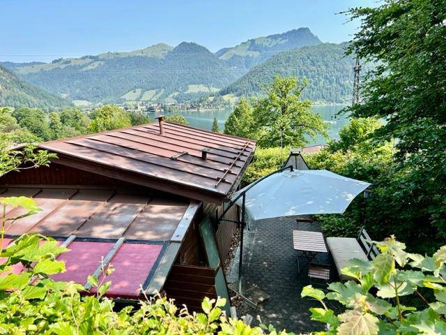 Terrasse der Hütte mit Sonnenschirm und Panoramablick auf See und Berge.