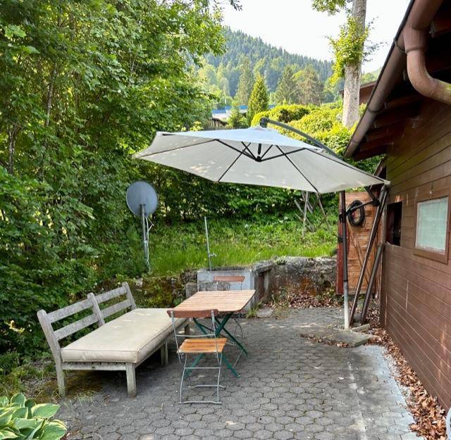 Gemütliche Terrasse mit Gartenmöbeln und Sonnenschirm, umgeben von viel Grün.