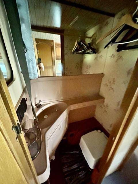 Kleines WC mit Waschbecken und einfacher Ausstattung in einem Wohnwagen.