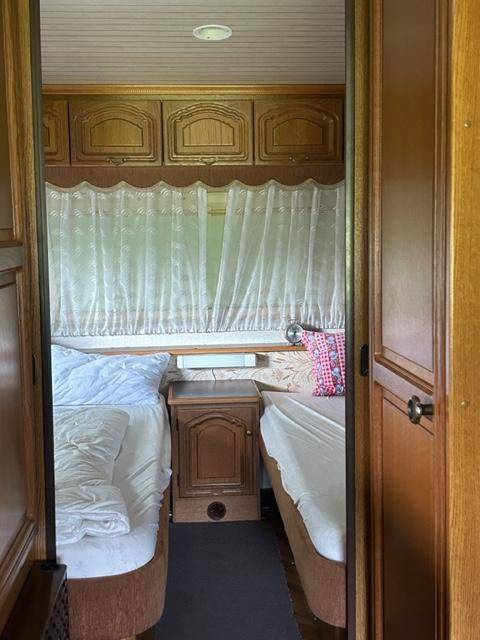 Schlafzimmer mit zwei Einzelbetten und Holzschränken in einem Wohnwagen.