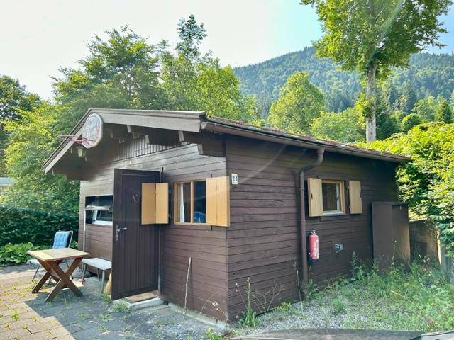Rustikale Holzhütte mit kleiner gepflasterter Terrasse und Sitzgelegenheiten.