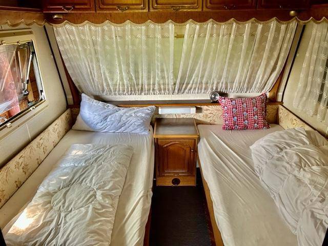 Gemütliches Schlafzimmer mit zwei Einzelbetten und Vorhängen in einem Wohnwagen.