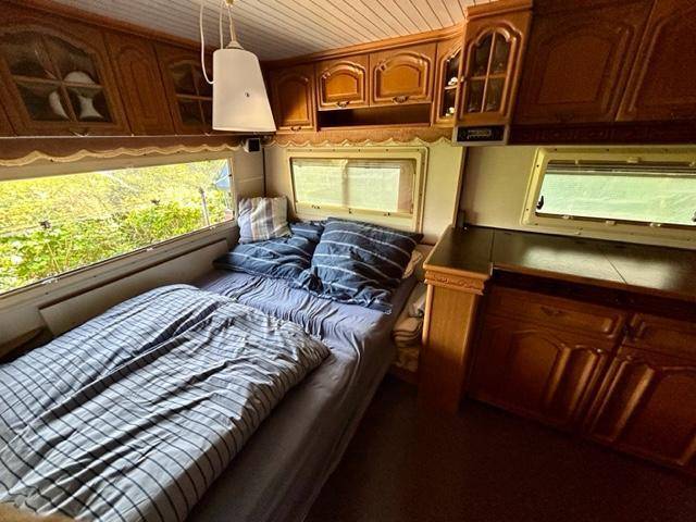 Gemütliches Schlafzimmer mit Doppelbett und Holzschränken in einem Wohnwagen.