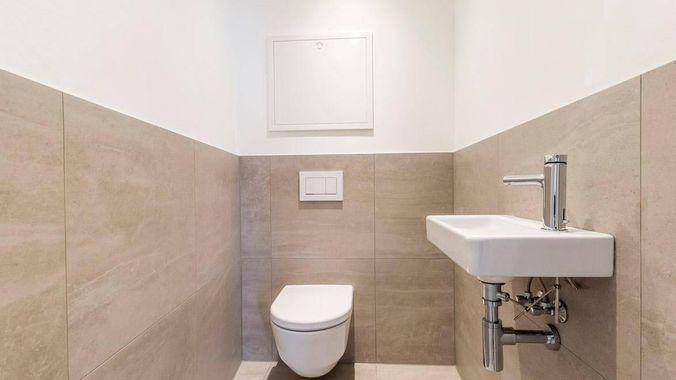Modernes Gäste-WC mit wandhängender Toilette und kleinem Waschbecken.
