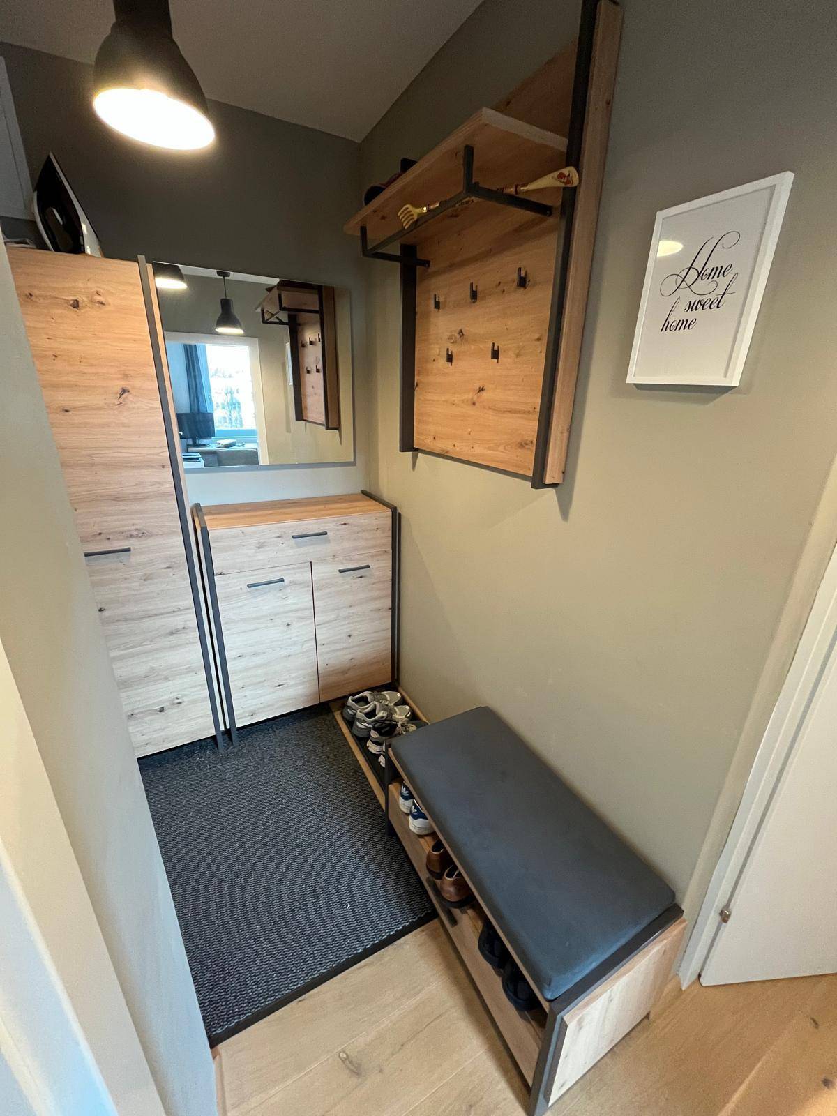Eingangsbereich mit Garderobe, Schuhregal und Spiegel, ausgestattet mit Holzelementen.
