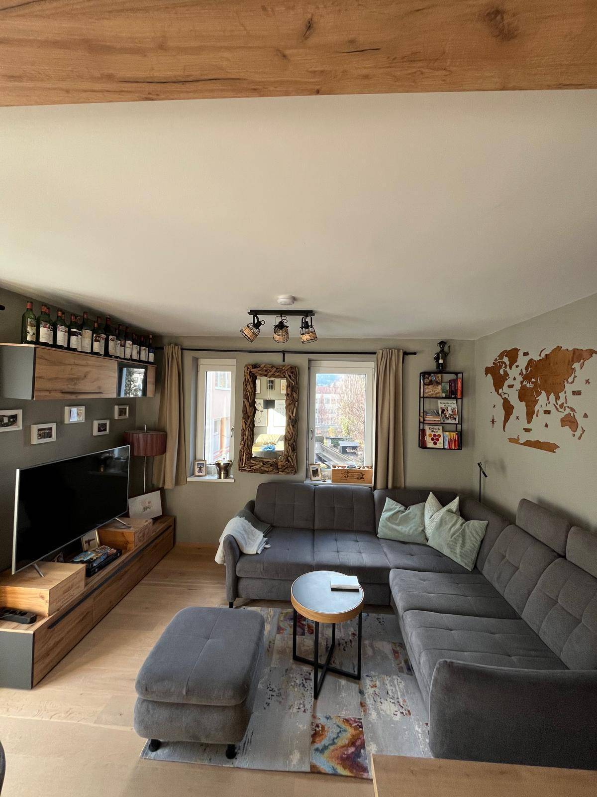Helles Wohnzimmer mit großem Ecksofa, Fernseher und dekorativer Weltkarte an der Wand.
