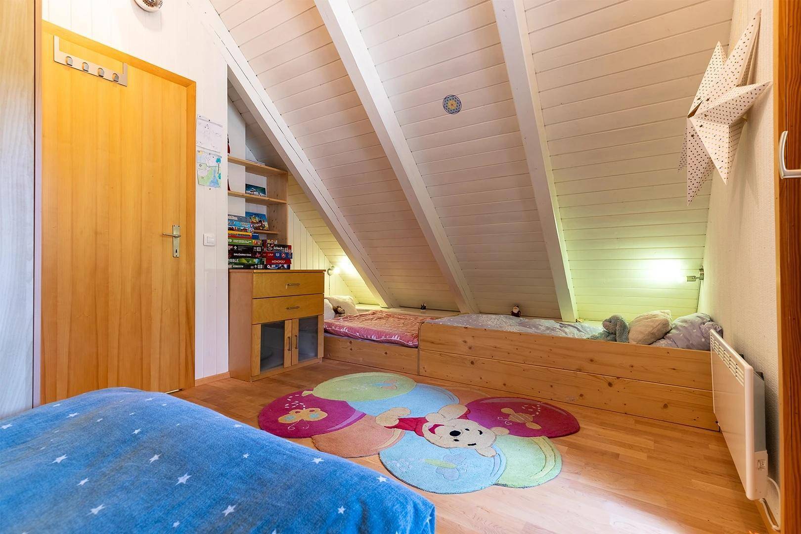 Helles Schlafzimmer im Dachgeschoss mit Holzfußboden, schrägen Wänden und eingebauten Betten.