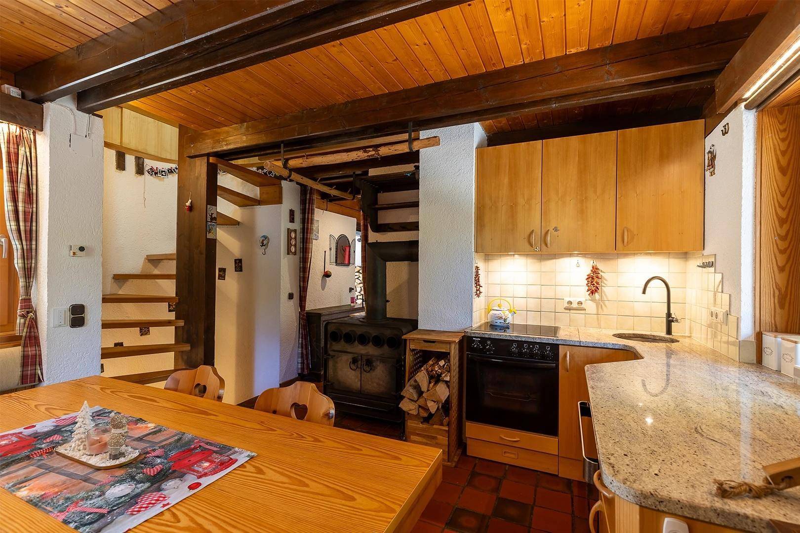 Traditionelle Küche mit Kachelofen, Holzmöbeln und Granitarbeitsplatte.