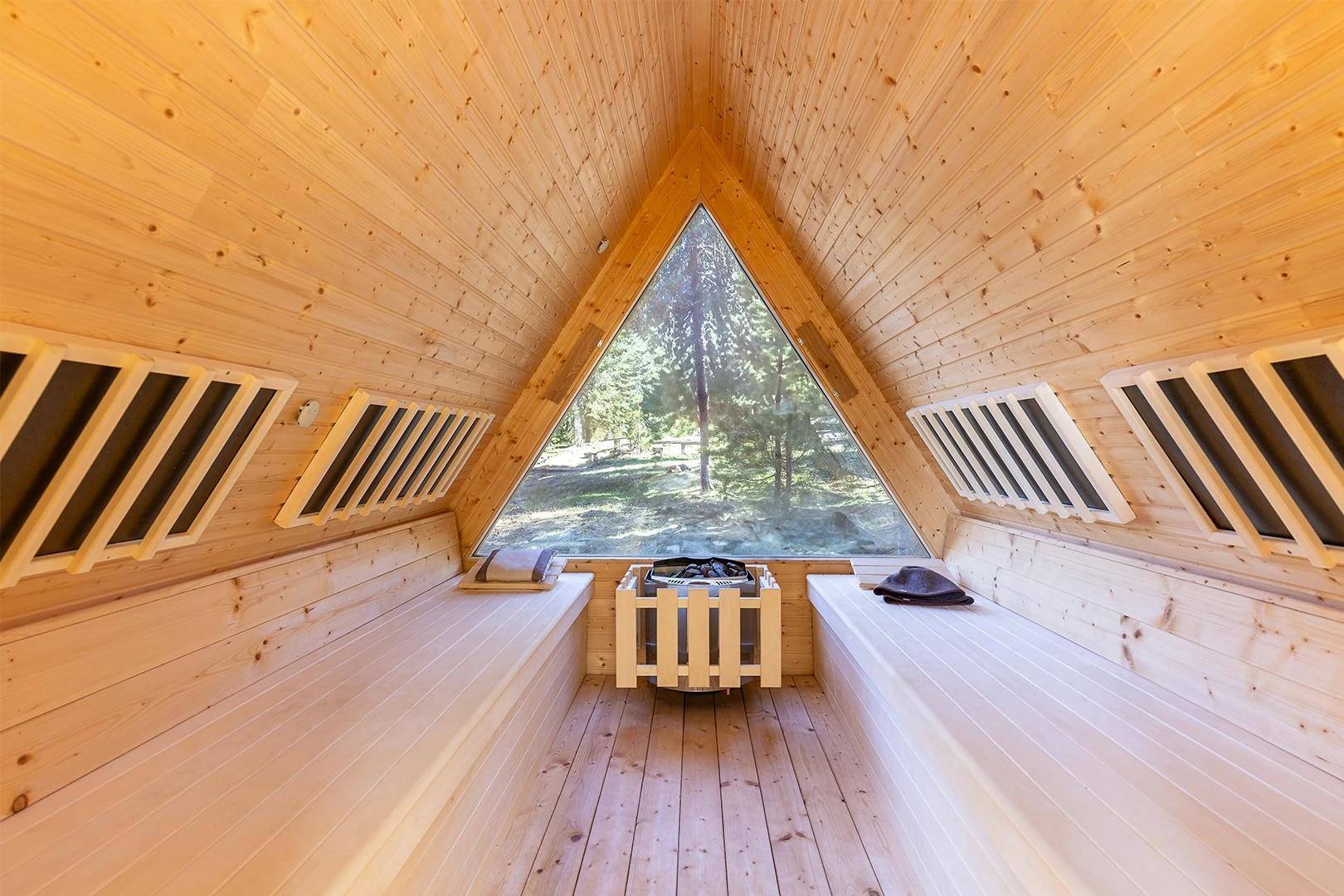 Moderne Sauna mit Holzverkleidung, großem Panoramafenster und Blick ins Grüne.