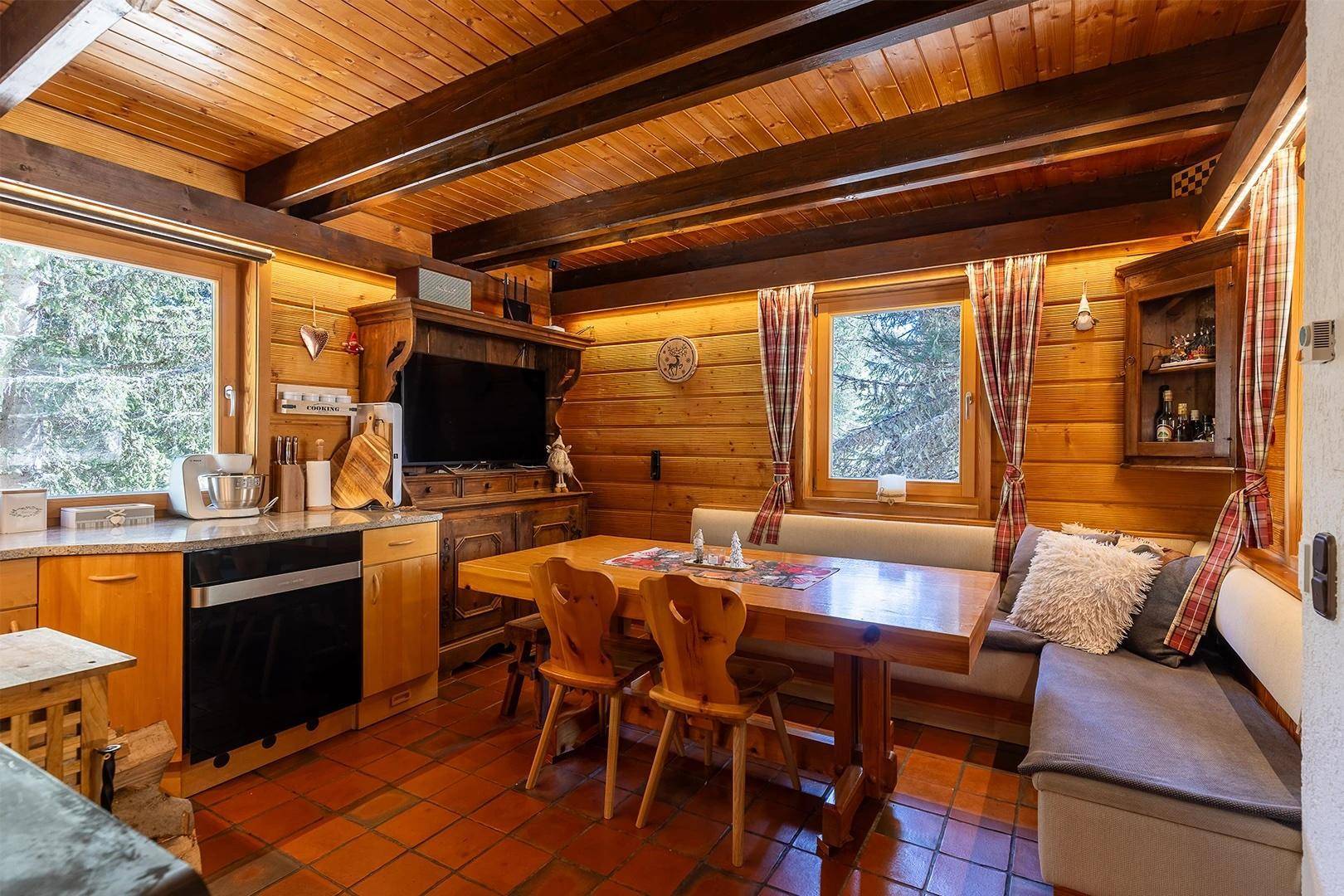 Rustikale Wohnküche mit Holzwänden, Holzbalkendecke und gemütlicher Essecke.