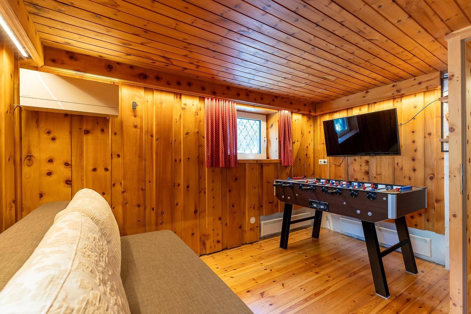Unterhaltungsraum mit Holzwänden, Fernseher und einem Tischfußballspiel.